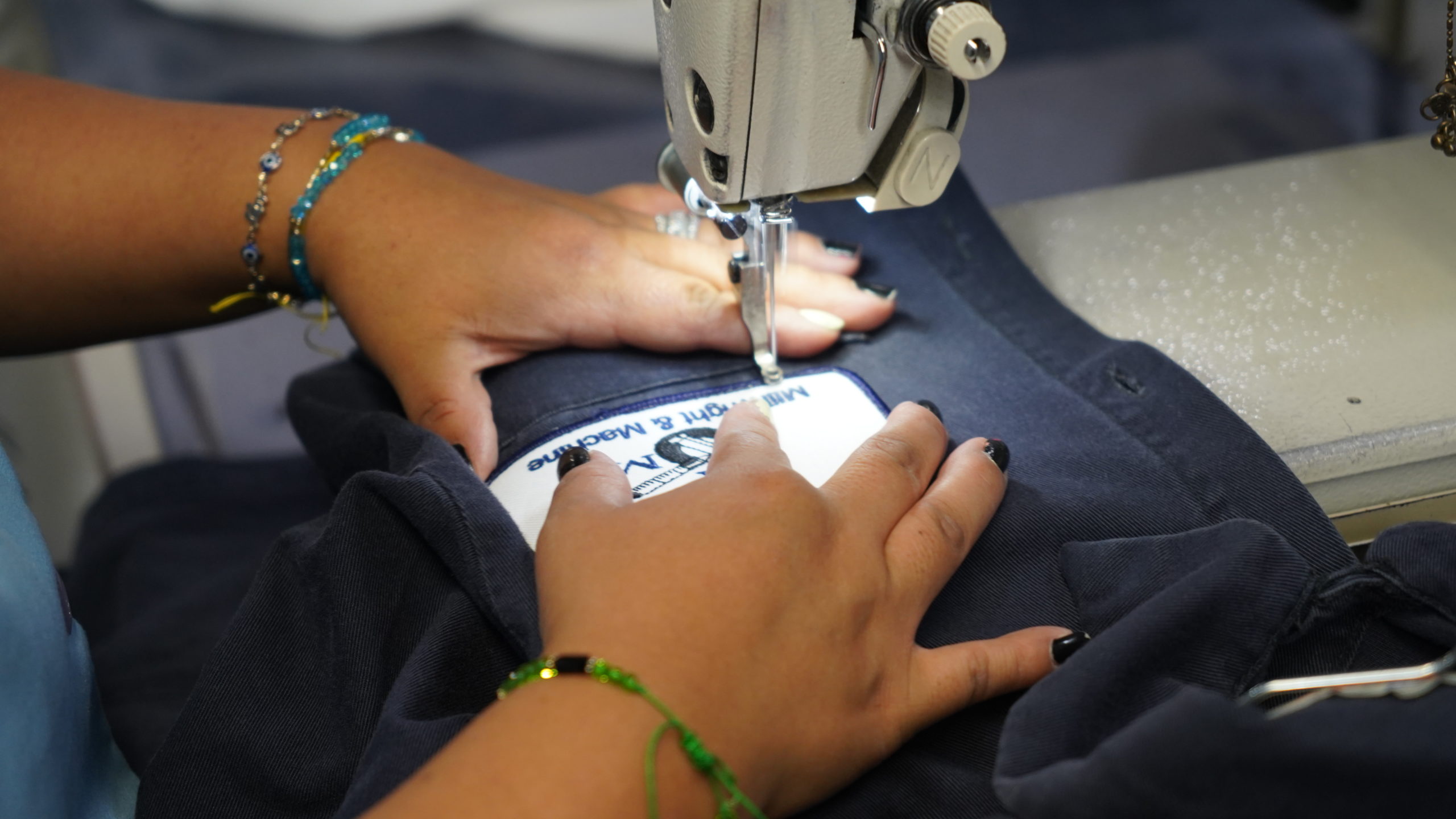 Lechner Services employee sewing a custom logo patch on a shirt