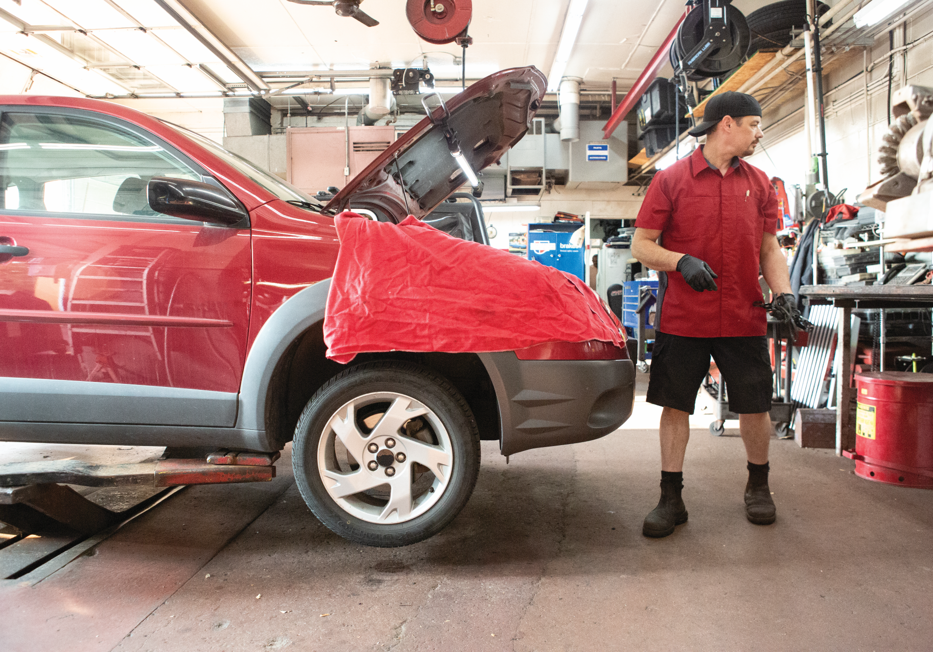 Uniformed mechanic working on a car with a fender cover