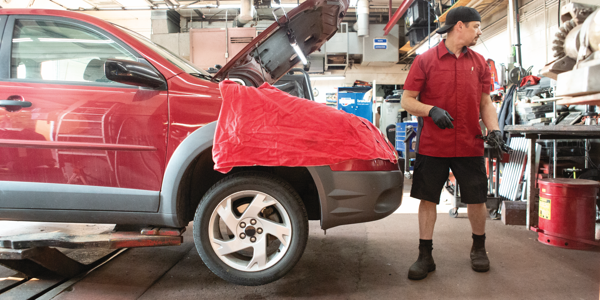 Uniformed mechanic working on a car with a fender cover